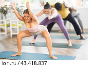 Woman performing Goddess Pose with forward bend in yoga studio. Стоковое фото, фотограф Яков Филимонов / Фотобанк Лори