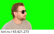 Surprised wow man over green background. Adult bearded guy in sunglasses gesturing on green screen chromakey. Handsome male looking pointed side to product placement isolated greenscreen. For Keying. Стоковое видео, видеограф Марина Демидюк / Фотобанк Лори