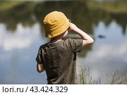 A 5-year-old boy in a yellow panama hat launches a radio-controlled boat in a pond. Children's fun and street games. Child's leisure time. Стоковое фото, фотограф Photojuli / Фотобанк Лори