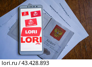 Телефон с логотипами фотобанка лори и паспорт лежат на агентском договоре (2024 год). Редакционное фото, фотограф Сергей Овчинников / Фотобанк Лори