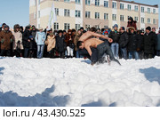 Соревнования по традиционной национальной чукотской борьбе тэйкэв на этническом празднике. Борцы с голым торсом борются на снегу. Холодная весна в Арктике. Город Анадырь, Чукотка, Россия. Редакционное фото, фотограф Андрей Степанов / Фотобанк Лори