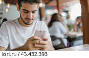 A man sits at a table, engrossed in his cell phone, with no distractions nearby. Стоковое AI-изображение, AI-художник Юрий Поздников / Фотобанк Лори