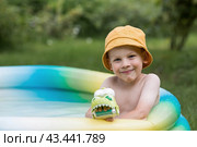 It's a hot day. A cute boy is swimming and splashing in the pool. A happy little boy smiles at the camera. Splashes of water are flying in all directions. The concept of summer holidays with children. Стоковое фото, фотограф Photojuli / Фотобанк Лори
