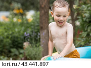 It's a hot day. A cute boy is swimming and splashing in the pool. A happy little boy smiles at the camera. Splashes of water are flying in all directions. The concept of summer holidays with children. Стоковое фото, фотограф Photojuli / Фотобанк Лори