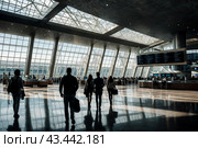 Interior of waiting room with silhouette people in terminal International Airport. Wait area with seats, passengers waiting airplane. Concept of Air Transportation industry. Copy ad text space. Стоковое AI-изображение, AI-художник Aleksandr Golubev / Фотобанк Лори