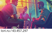 Three friends enjoy a late night conversation in a room illuminated by vibrant neon lights. Стоковое AI-видео, аниматор Данила Большаков / Фотобанк Лори