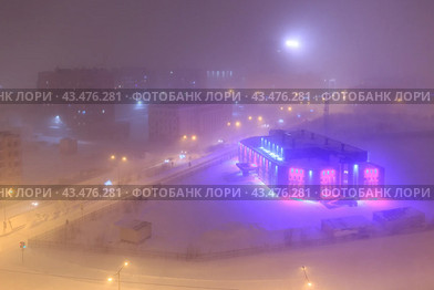 Вид сверху на ночной город. Снегопад и туманная дымка холодным зимним вечером в Арктике. Красочное уличное освещение большого северного города. Норильск, Красноярский край, Сибирь, Россия. Стоковое фото, фотограф Андрей Степанов / Фотобанк Лори