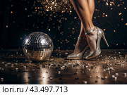 Women's legs in luxurious shiny pumps with heels at a party or disco on the background of a silver mirrored disco ball. The queen of the dance floor. Стоковое AI-изображение, AI-художник Photojuli / Фотобанк Лори