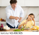 Father forcing little daughter to eat vegetable salad in kitchen. Стоковое фото, фотограф Татьяна Яцевич / Фотобанк Лори