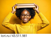 A pretty black African American girl with glasses and books in her hands. The child goes to school for the first time. A child on a yellow monochrome background. Back to school. Стоковое AI-изображение, AI-художник Photojuli / Фотобанк Лори
