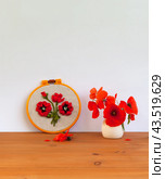 Summer still life with floral handmade embroidery with satin ribbons of red poppy flowers in hoops and bouquet of fresh poppies in a vase on wooden table. Crafts and embroidery as a hobby and leisure. Стоковое фото, фотограф Виктория Катьянова / Фотобанк Лори