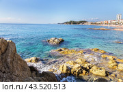 Rocky coast and sandy beach of the small Spanish resort of Lloret de Mar on a sunny summer day (2017 год). Редакционное фото, фотограф Лариса Гордеева / Фотобанк Лори