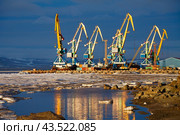 Sea port in the Arctic. June. Ice floes on the water near the shore and the pier. Port cranes are illuminated by the sun. Maritime transport infrastructure in the Far North of Russia. Anadyr, Chukotka. Стоковое фото, фотограф Андрей Степанов / Фотобанк Лори