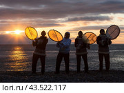 Uelen, Chukotka Peninsula, Russia - July 9, 2009. Musicians of the Chukchi-Eskimo folk ensemble Uelen on the seashore. Men with yarars (traditional musical instruments of the peoples of Chukotka). Редакционное фото, фотограф Андрей Степанов / Фотобанк Лори