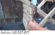 Restoration and repair of a wooden vintage chair. The man tries on a metal plate to strengthen the structure. The chair lies on a workbench. Стоковое видео, видеограф Vadzim Yakubovich / Фотобанк Лори