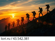 A group of climbers climbing the side of a mountain against the backdrop of the rising or setting sun. The climbers are silhouetted against the bright orange and yellow sky, creating a dramatic and inspiring atmosphere. The group walks along a rocky slope, connected by a rope for safety, symbolizing teamwork and overcoming difficulties. The landscape around them is majestic, with mountain peaks and slopes adding to the epic feel of the scene. Стоковое AI-изображение, AI-художник Анна Кривицкая / Фотобанк Лори