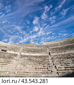 Roman Theatre in Amman, Jordan -- theatre was built the reign of Antonius Pius (138-161 CE), the large and steeply raked structure could seat about 6000 people. Against the sky with clouds (2016 год). Стоковое фото, фотограф Владимир Журавлев / Фотобанк Лори