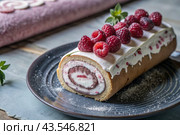 Swiss sponge roll with raspberries, a delicious fruit and cream dessert filled with cream cheese, decorated with fresh raspberries. Стоковое AI-изображение, AI-художник Photojuli / Фотобанк Лори