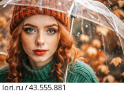 Autumn portrait in the rain. Close-up of a young red-haired woman with expressive green eyes in a knitted hat under an umbrella. Стоковое AI-изображение, AI-художник Photojuli / Фотобанк Лори