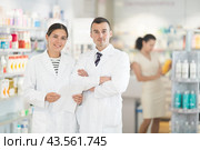 Positive man and girl pharmacists are standing in pharmacys sales hall, pharmacy staff are amicably preparing to meet chemist shop visitors. Стоковое фото, фотограф Яков Филимонов / Фотобанк Лори