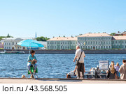 Женщина сидит под зонтиком и приглашет гостей города на прогулку на теплоходе по Неве. Санкт-Петербург (2024 год). Редакционное фото, фотограф Ольга Визави / Фотобанк Лори