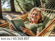 An elderly pensioner, a modern grandmother with glasses, reads a book on vacation in a hammock by the sea in natural light. Стоковое AI-изображение, AI-художник Photojuli / Фотобанк Лори