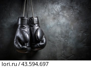 Professional black boxing gloves hang on a black background with a space to copy. Стоковое AI-изображение, AI-художник Photojuli / Фотобанк Лори