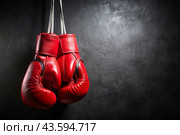 Professional red boxing gloves hang on a black background with a space to copy. Стоковое AI-изображение, AI-художник Photojuli / Фотобанк Лори