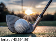 The banner. A white ball and a metal golf club are lying on the lawn in the hands of a man against the sunset background. An advertisement for a golf game at a country club. Free space for text. Стоковое AI-изображение, AI-художник Photojuli / Фотобанк Лори