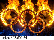 A fire show. The burning rings of the Olympic Sports Games. Стоковое AI-изображение, AI-художник Photojuli / Фотобанк Лори