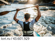A kayaker celebrates his victory with an oar in his hands on a blurred background of the river. Kayaker at the Summer Olympics. Стоковое AI-изображение, AI-художник Photojuli / Фотобанк Лори