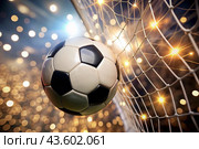 Goal. A soccer ball in the goal net, against a background of sparkling lights and a blurred background. Стоковое AI-изображение, AI-художник Photojuli / Фотобанк Лори