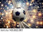 Goal. A soccer ball in the goal net, against a background of sparkling lights and a blurred background. Стоковое AI-изображение, AI-художник Photojuli / Фотобанк Лори