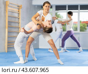 Young woman applying inverted headlock during mock bout in self-defense training. Стоковое фото, фотограф Яков Филимонов / Фотобанк Лори