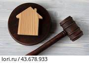 Judge's hammer lies on a light wooden table against the background of the house. Стоковое фото, фотограф Жанна Гапанович / Фотобанк Лори