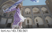 A young woman with long hair in an oriental robe and a skullcap walks through an ancient oriental city. Стоковое видео, видеограф Aleksey Kidisyuk / Фотобанк Лори