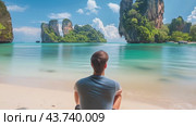 A man is comfortably sitting on a lovely beach while gazing out at the vast ocean before him. Стоковое AI-видео, аниматор Юрий Поздников / Фотобанк Лори
