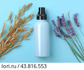 An opaque plastic pump bottle for white liquid soap on a blue background next to branches of oats and lavender. Стоковое AI-изображение, AI-художник Ярославский Максим / Фотобанк Лори