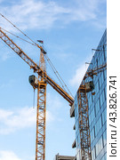 During the day, a crane is seen in front of a building under construction. Стоковое фото, фотограф Аксенова Вера / Фотобанк Лори