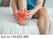 Foot pain, corns and calluses, dry skin on legs, man suffering from feet ache at home. Стоковое фото, фотограф Станислав Тарко / Фотобанк Лори