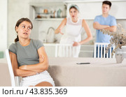 Distressed young girl sitting in home kitchen with discontented brother and mother. Стоковое фото, фотограф Яков Филимонов / Фотобанк Лори