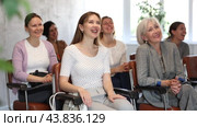 Laughing young girl participating in study session, sitting in auditorium with group of women and listening to lecturer. Стоковое видео, видеограф Яков Филимонов / Фотобанк Лори