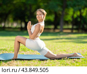 Girl in park on green grass of lawn performs Anjaneyasana. Стоковое фото, фотограф Яков Филимонов / Фотобанк Лори
