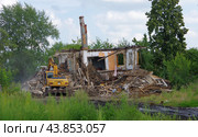 Экскаватор "Hyundai" разрушает ветхий дом в городе Туринск, Свердловская область (2024 год). Редакционное фото, фотограф Алексей Иванов / Фотобанк Лори