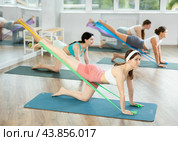 Girl leads class women, standing on all fours, performing exercises with wide elastic skip rope. Стоковое фото, фотограф Яков Филимонов / Фотобанк Лори