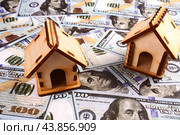 Two wooden houses on a background of hundred dollar bills. The concept of a mortgage. Стоковое фото, фотограф Ярославский Максим / Фотобанк Лори
