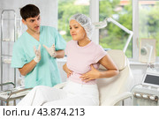 Young male doctor consulting female client on breast augmentation. Стоковое фото, фотограф Яков Филимонов / Фотобанк Лори