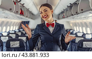 A flight attendant greets passengers with a smile in the cabin of an airliner during boarding. Стоковое AI-изображение, AI-художник Ярославский Максим / Фотобанк Лори