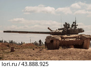 Российский танк Т-72 или Т-80 повернув ствол в сторону и военные позади него (2019 год). Редакционное фото, фотограф Евгений Зимин / Фотобанк Лори
