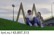 Two lovers kissing in the park on the grass against the backdrop of the urban landscape. Стоковое видео, видеограф Strunov David / Фотобанк Лори
